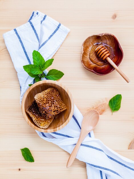 Honeycomb in bowl with herbs on wooden background.