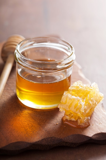 Honeycomb dipper and honey in jar on wooden table