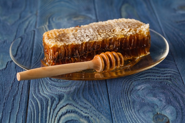 Honeycomb and honey dipper on wooden background