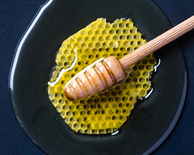 Соты в меду с медовым ковшом на ретро-черном фоне. вид сверху