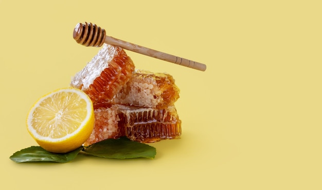 Honeycomb and lemon with wooden stick on yellow background