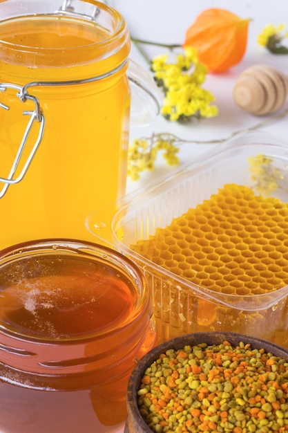 Соты, пыльца и банки с медом. диппер мед и цветы