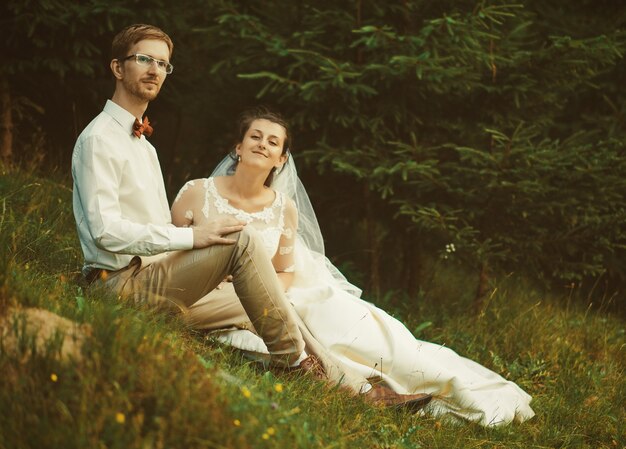 Honeymoon. The bride and groom sitting on grass. Summer time.