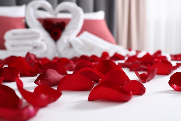 honeymoon swans made with towels and beautiful rose petals on bed in room selective focus