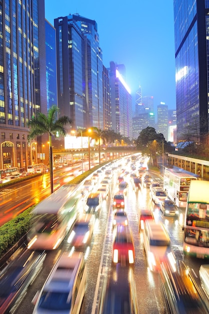 Hong Kong straat met druk verkeer en wolkenkrabber kantoor in de schemering.