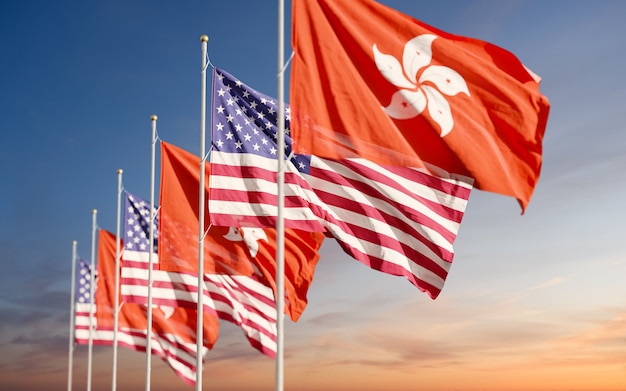 Флаги Гонконга и США, развевающиеся на фоне облачного неба