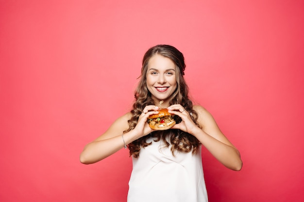 Hongerig meisje dat met geopende mond grote hamburger eet.