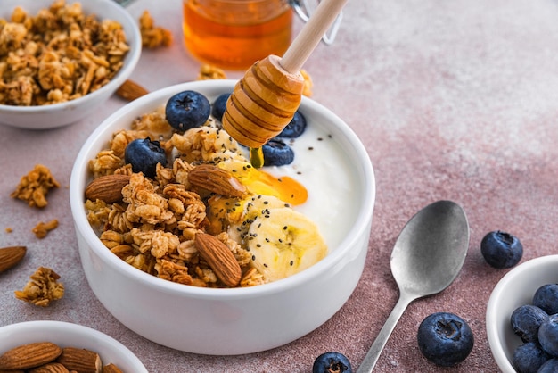 Honing gieten in de kom Griekse yoghurt met havermout granola banaan bosbessen noten chia zaden