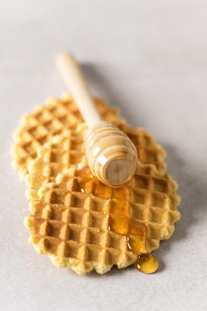Honing gieten op een vers wafelsontbijt met Belgische wafels Grijze achtergrond verticaal