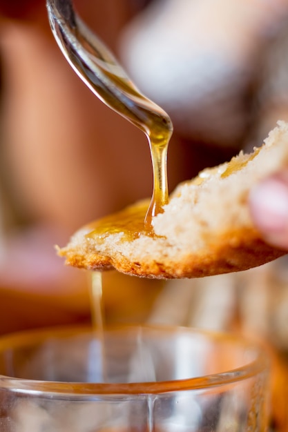 Honing stroomt van een lepel naar brood. Honing - een goed voedsel met geneeskrachtige eigenschappen