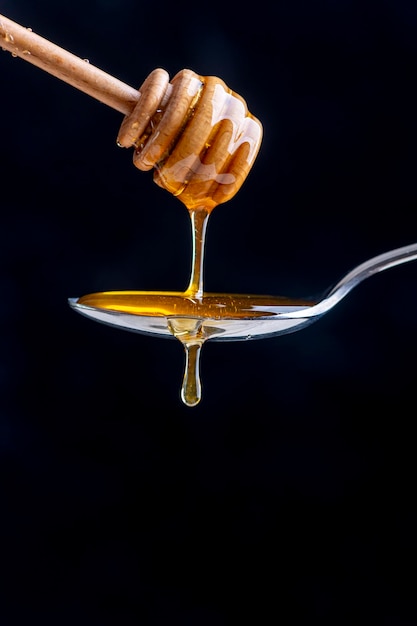 Honing uit een houten honingpot in een lepel gieten