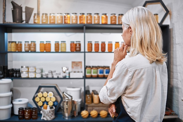 Honing winkel eigenaar kruidenierswinkel of vrouw denken op plank ideeën verkoop product prijs of voorraadbeheer Volwassen klein bedrijf of biologische supermarkt werknemer planning bijensiroop container promotie