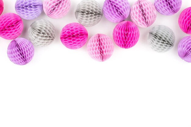 Honingraat ballen decoratie grens. Roze, lila en grijze papieren pom pom op een witte achtergrond. Plat leggen. Vakantie concept