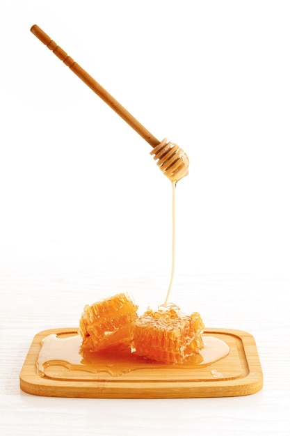 Honingraat en houten dipper met druipende honing geïsoleerd op een witte achtergrond
