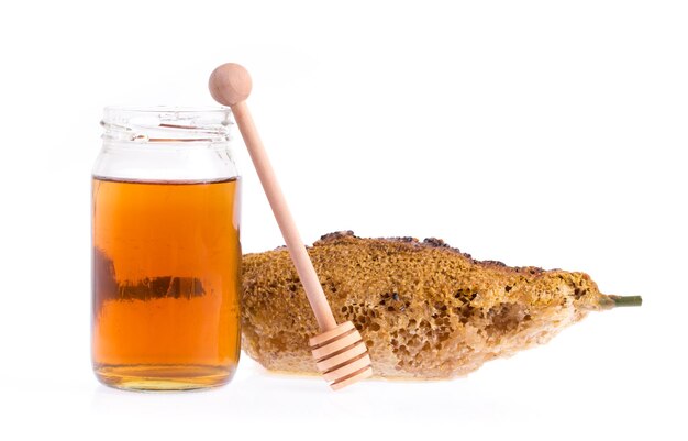 Foto honingraten met fles honing en houten dipper geïsoleerd op een witte achtergrond