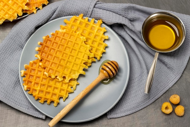 Honingsdipper en wafels op groene plaat Honing in metalen kom