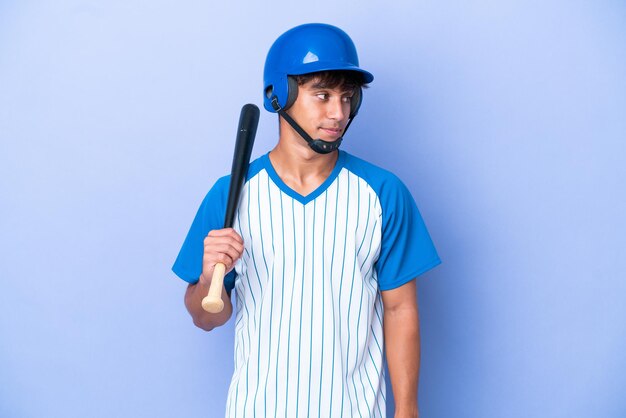 Honkbal blanke man speler met helm en vleermuis geïsoleerd op blauwe achtergrond op zoek naar de kant