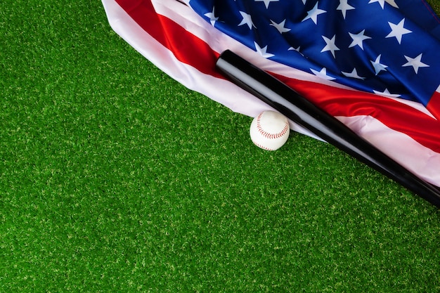 Honkbalknuppel en bal met Amerikaanse vlag op gras