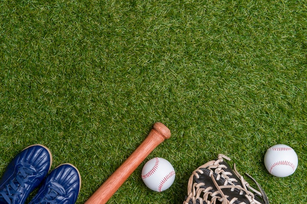 Honkbalknuppel, schoenen, handschoen en bal op groen grasveld