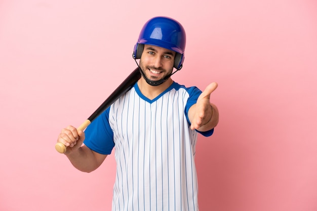 Honkbalspeler met helm en vleermuis geïsoleerd op roze achtergrond handen schudden voor het sluiten van een goede deal