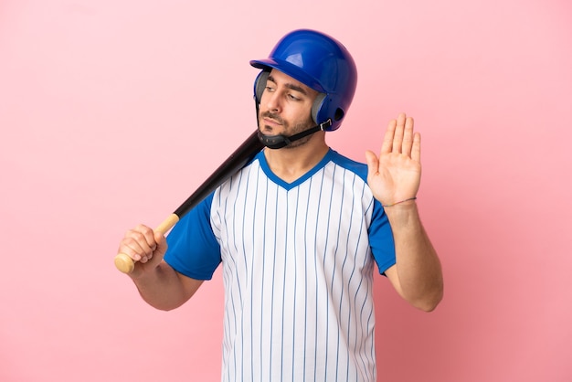 Honkbalspeler met helm en vleermuis geïsoleerd op roze achtergrond stop gebaar maken en teleurgesteld