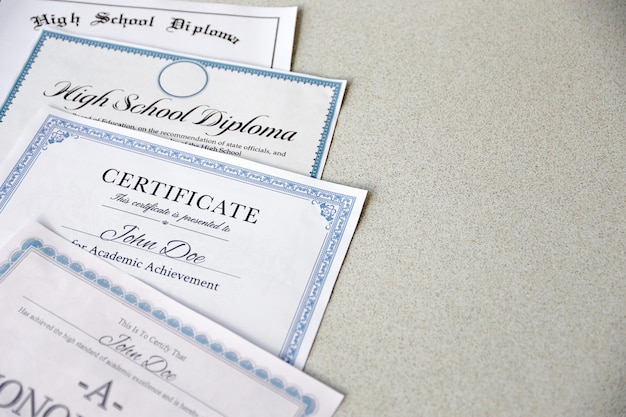 A honor roll recognition certificate of achievement and high school diploma lies on table Education documents