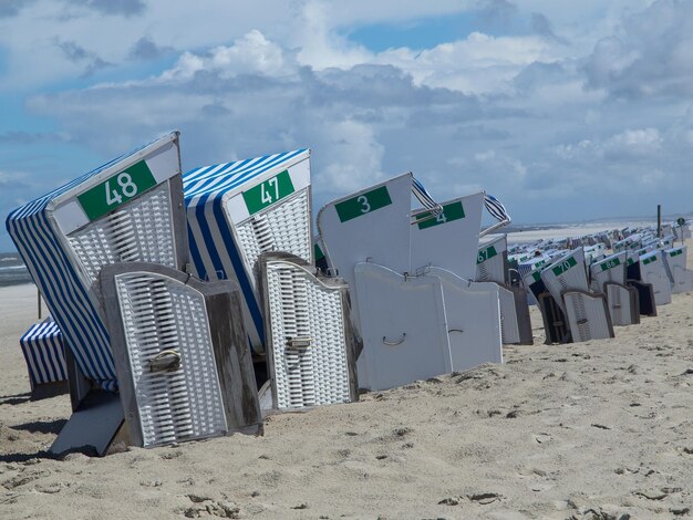 Hooded chairs on beach against sky