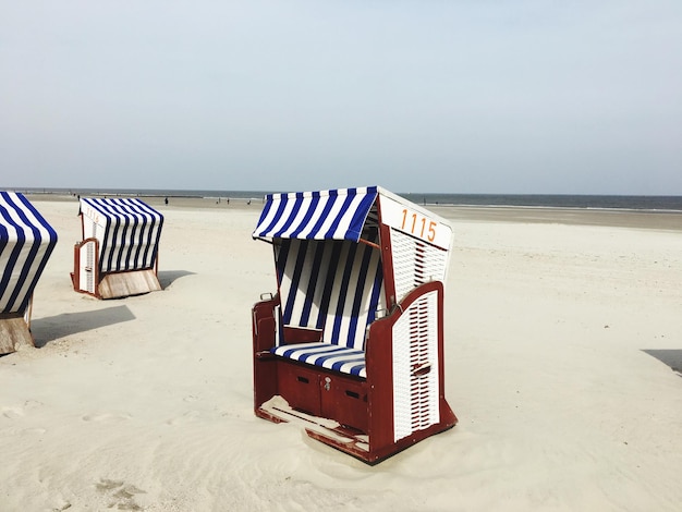 Foto sedie con cappuccio sulla spiaggia contro il cielo
