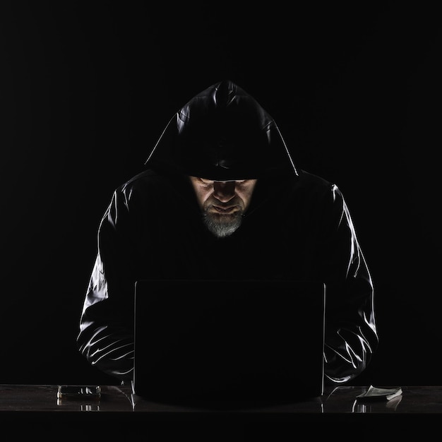 hooded masked hacker with laptop