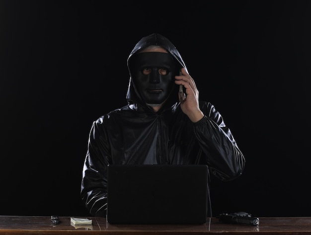 Photo hooded masked hacker with laptop