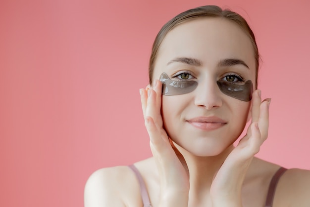 Hoofd geschoten portret close-up lachende jonge vrouw met onder de ogen hydraterende patches masker