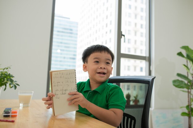 Hoofd geschoten Portret van een gelukkig Aziatisch schattig kind dat thuis huiswerk maakt met een glimlach.