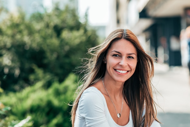 Hoofd geschoten van mooie glimlachende brunette buitenshuis.