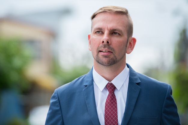 Hoofd schot van zakenman met blauw pak buitenshuis denken