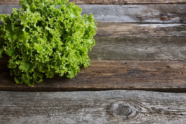 Hoofd van groene verse salade met wortel op oude ruwe houten oppervlakte, gezond het eten concept, selectieve nadruk