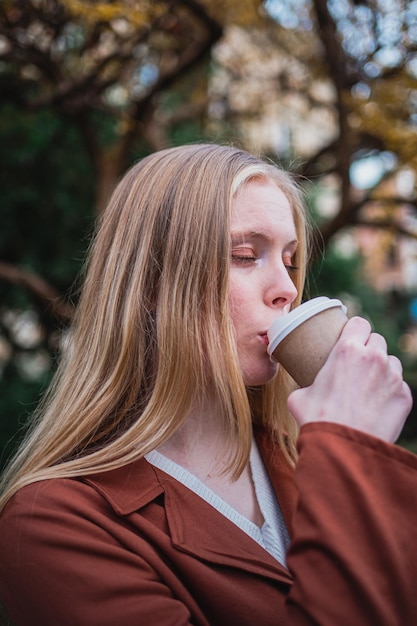 Hoofdfoto van een meisje dat koffie drinkt terwijl haar ogen gesloten zijn. Ze geniet ervan