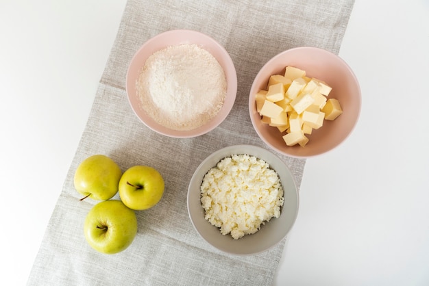 Hoofdingrediënten voor appeltaart. Borden met bloem, boter, kwark en appels. Bovenaanzicht.