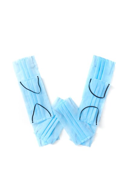 Hoofdletter W handgemaakt van medische antibacteriële beschermende blauwe gezichtsmaskers op een witte muur, kopieer ruimte. Creatief alfabet voor het verzinnen van nieuwe woorden.