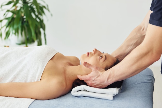 Hoofdmassage jonge vrouw ligt wanneer man haar procedure in spa doet