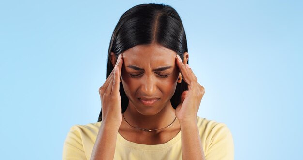 Foto hoofdpijn pijn en burn-out vrouw met vermoeidheid in de studio met gezondheid nood en wellness op blauwe achtergrond migraine hersenmist en duizeligheid van medische aandoening met burn-out ziek en moe