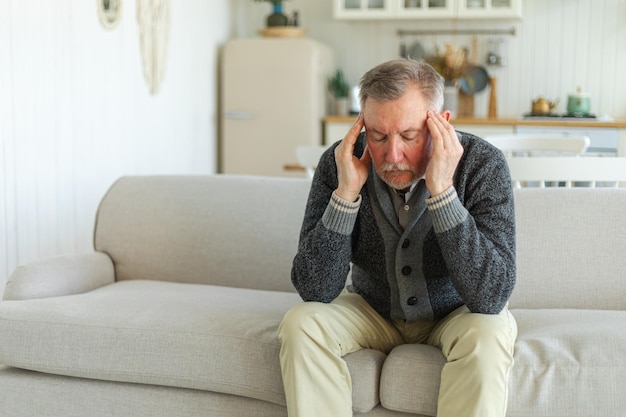 Foto hoofdpijn pijn ongelukkige senior man van middelbare leeftijd die lijdt aan hoofdpijn ziek wrijven tempels thuis ma