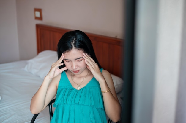 Hoofdpijn vrouw Close-up foto van een mooie vrouw die op een bed in de slaapkamer zit met haar ogen dicht en haar hoofd aanraakt terwijl ze lijdt aan migraine