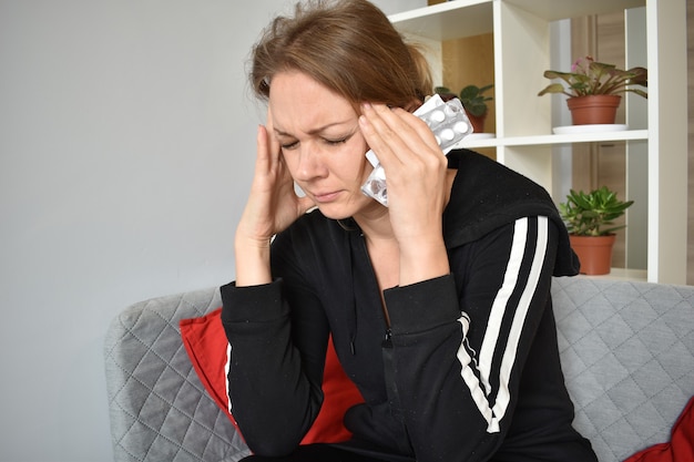 Foto hoofdpijn. vrouw die met tabletten zijn hoofd houdt. de symptomen van het virus en de ziekte.