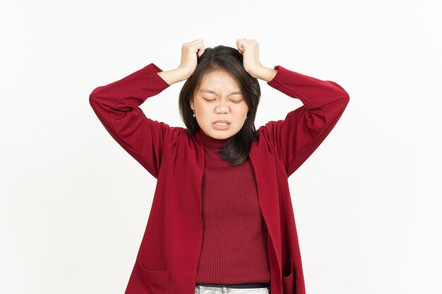 Hoofdpijngebaar van mooie Aziatische vrouw die rood overhemd draagt dat op witte achtergrond wordt geïsoleerd