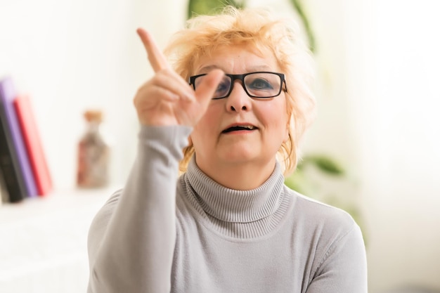 Hoofdschot volwassen vrouw die naar de camera kijkt en praat, grootmoeder chat met familielid online, videogesprek voeren, blogger van middelbare leeftijd die vlog opneemt, leraar die tegen webcam spreekt, lezing op afstand.