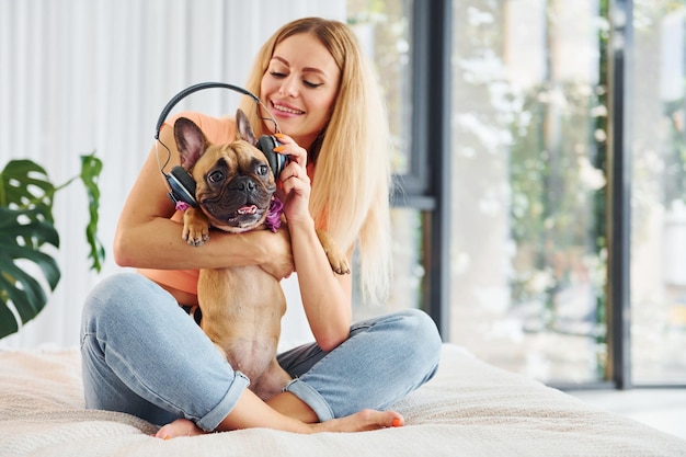 Hoofdtelefoon op huisdier zetten Vrouw met mopshond is overdag thuis