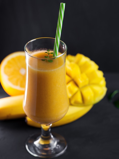 Hoog glas smoothie cocktail met mangosinaasappel en banaan. Exotisch gezond ontbijt