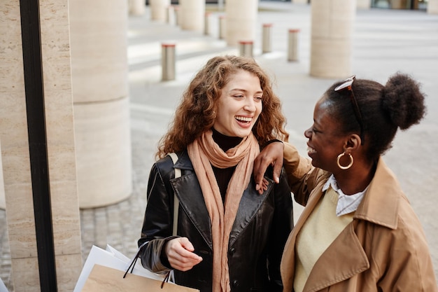 Hoog hoekportret van twee jonge vrouwen die lachen in de stad met warme tinten