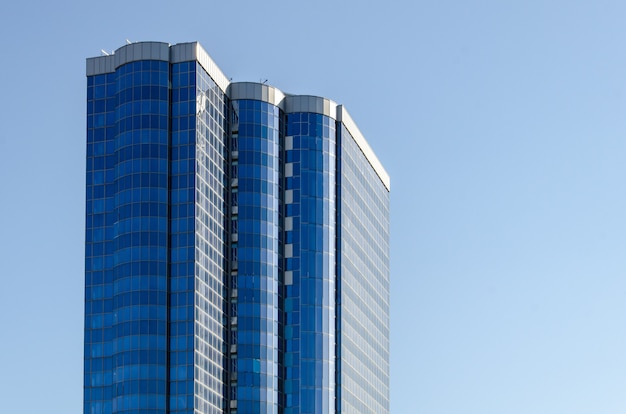 Hoogbouw met blauwe glazen gevel tegen blauwe lucht. Modern woongebouw met meerdere verdiepingen