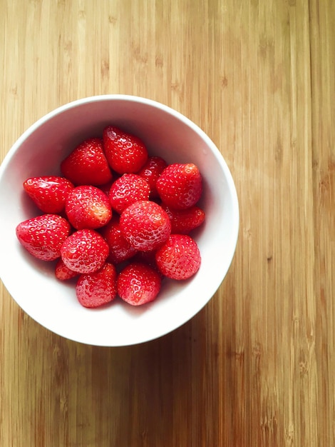 Hooghoekbeeld van aardbeien in een schaal op een houten tafel